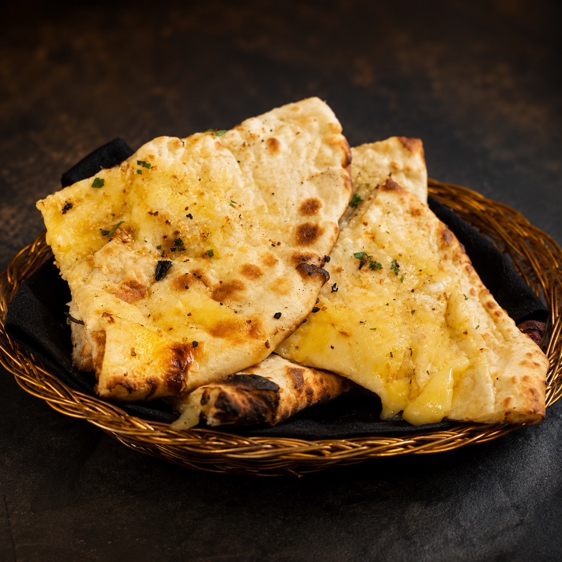 Cheese naan in a brass basket, fresh from the tandoor