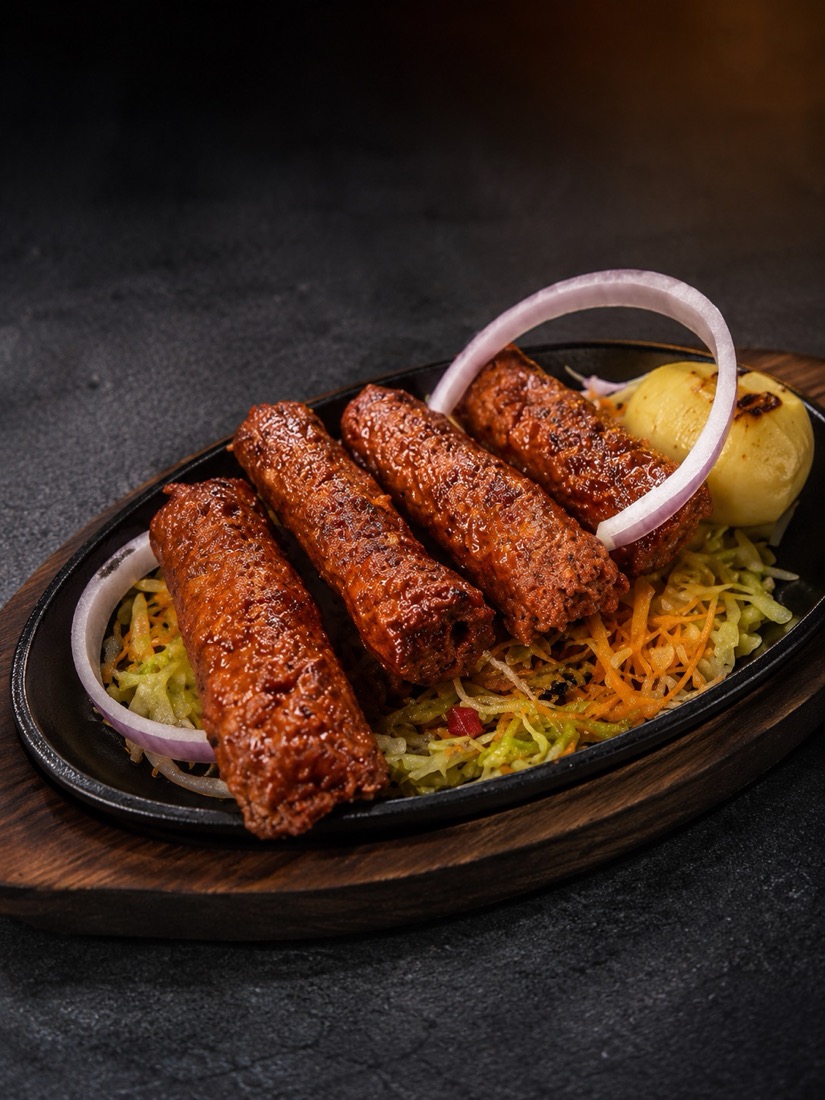Seekh kebabs on a sizzling plate with onion rings