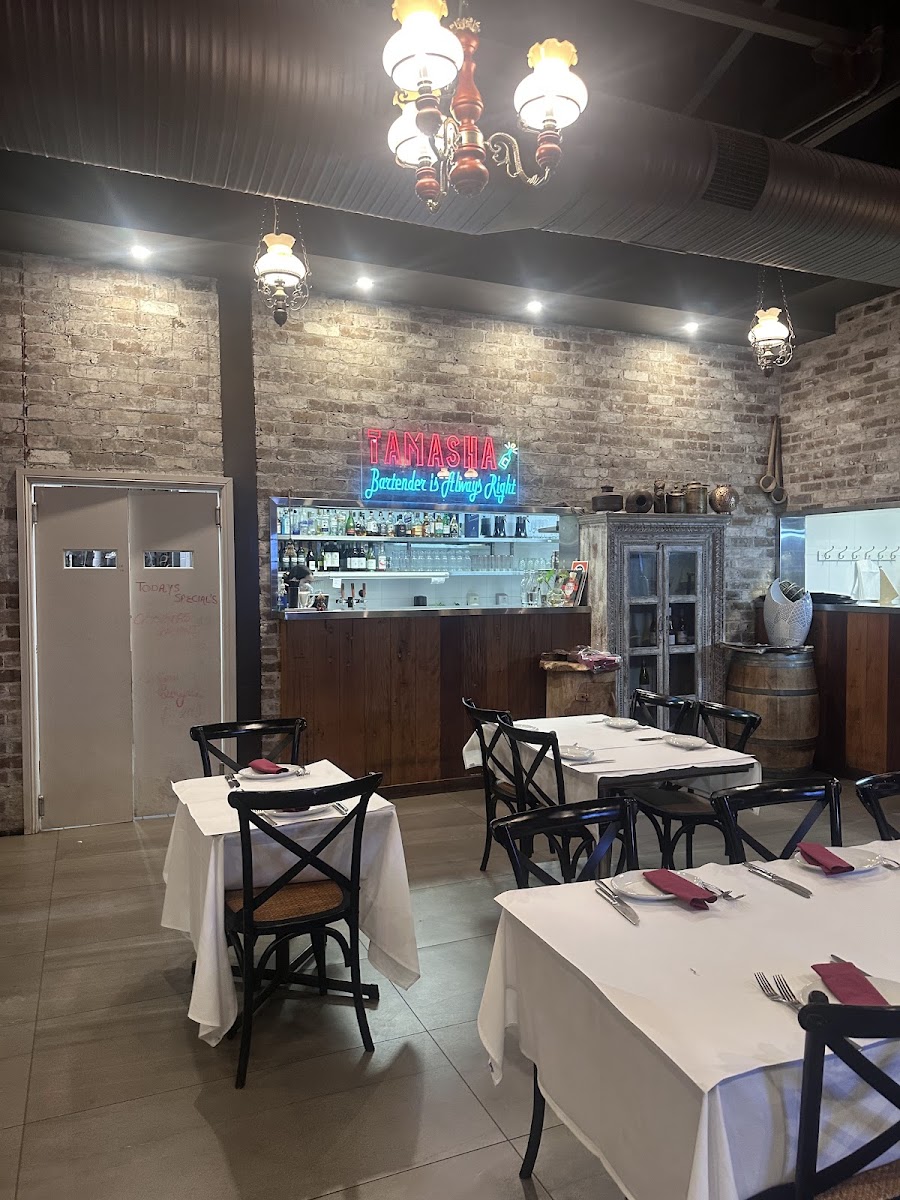 The TAMASHA bar with its neon sign, exposed brick and antique cabinet